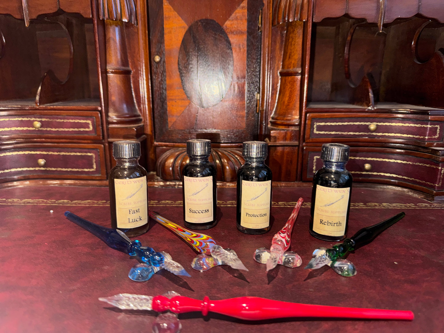 Set of potion bottles and multicolored glass dip pens on a wooden surface.