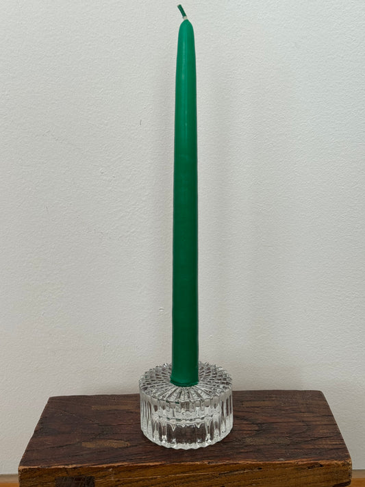 Green candle in a decorative holder on a wooden surface with a white background
